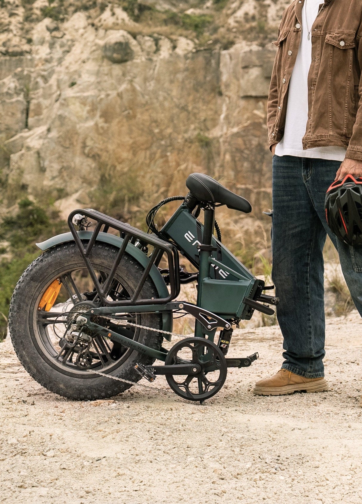 ENGWE Engine Pro 2.0 electric bike folded with thick tires and rear rack next to person holding helmet