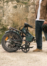 ENGWE Engine Pro 2.0 electric bike folded with thick tires and rear rack next to person holding helmet