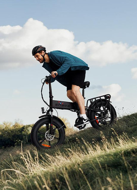 Man riding ENGWE Engine X electric bike off road on grassy hill wearing helmet and casual gear